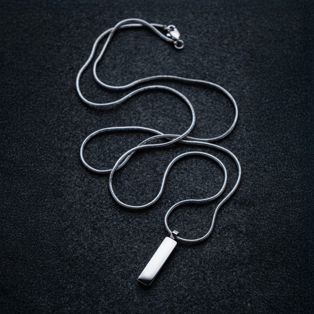 Silver necklace with a rectangular pendant on a dark background