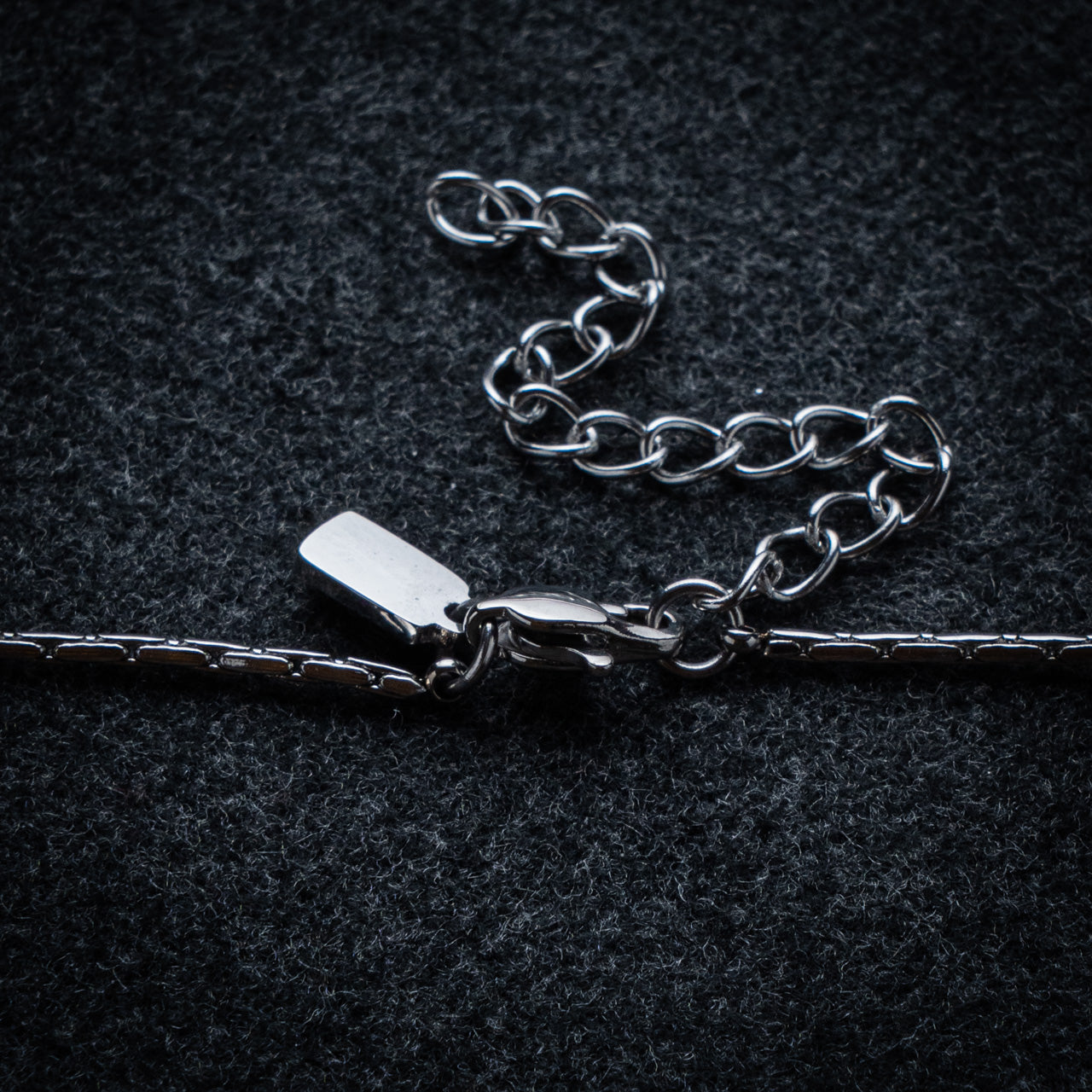 Silver chain necklace on a dark textured background