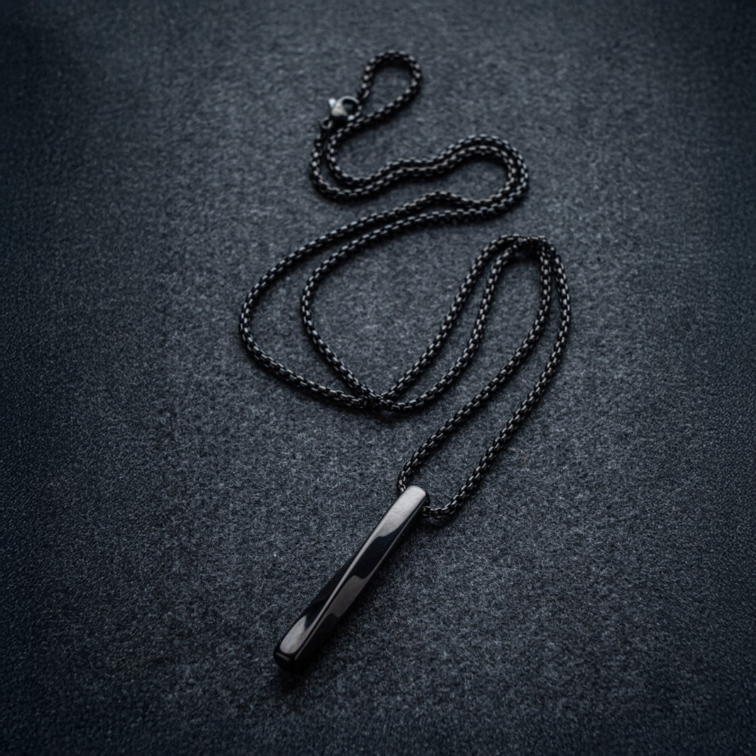 Black chain necklace with a pendant on a dark textured surface