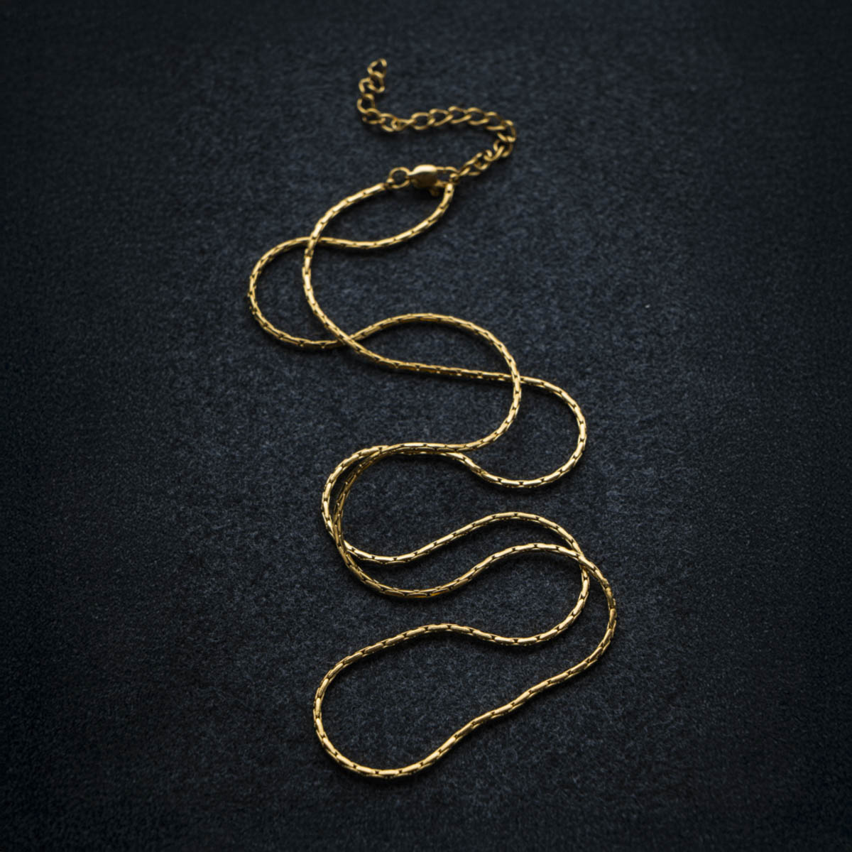 Gold chain necklace on a dark textured background